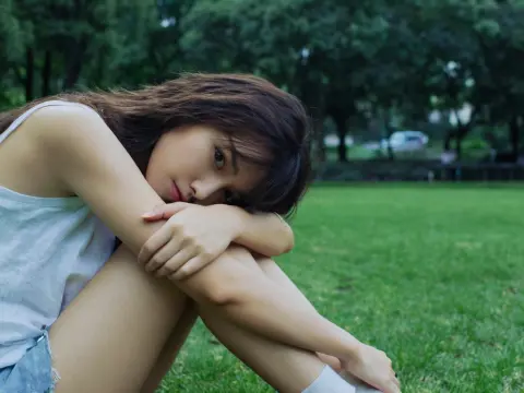 公園で体躯座りして、コチラを見つめている女性
